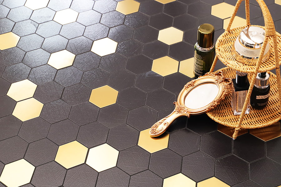Arrangement of black and gold hexagon tiles with a wicker tray holding mirror and cosmetics 