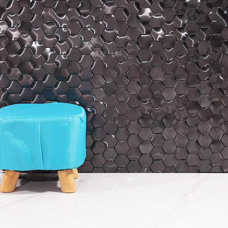 Modern glossy black hexagon tiles on the wall with a bright blue stool 