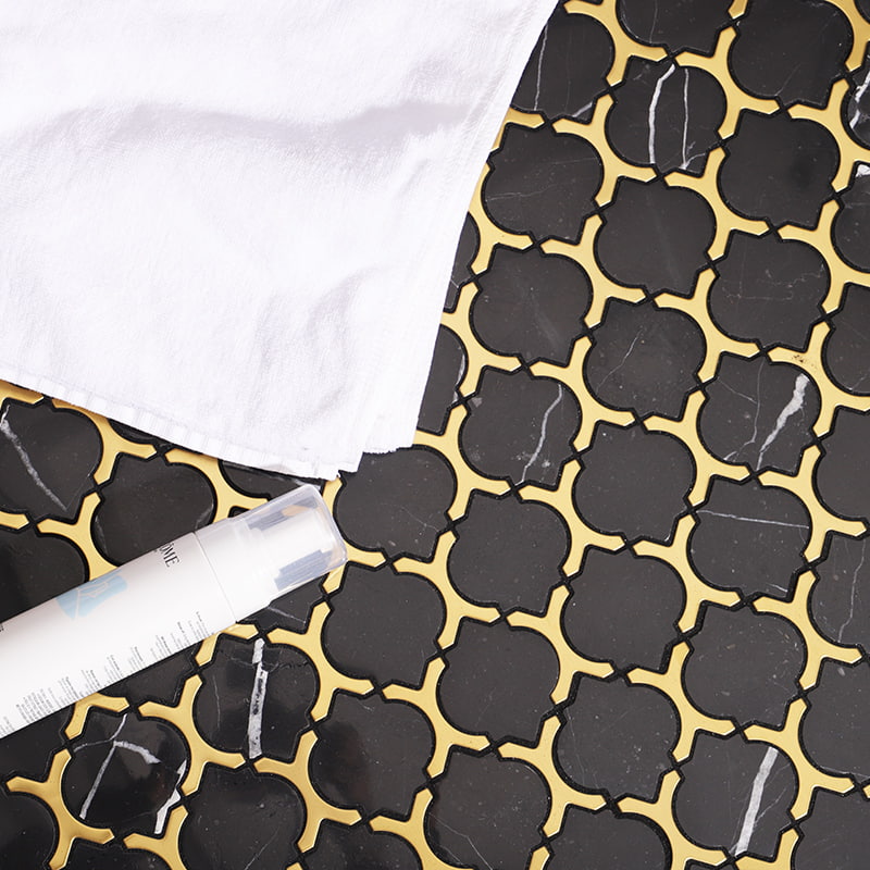 Black marble arabesque tile with bold gold grout lines, top-down view