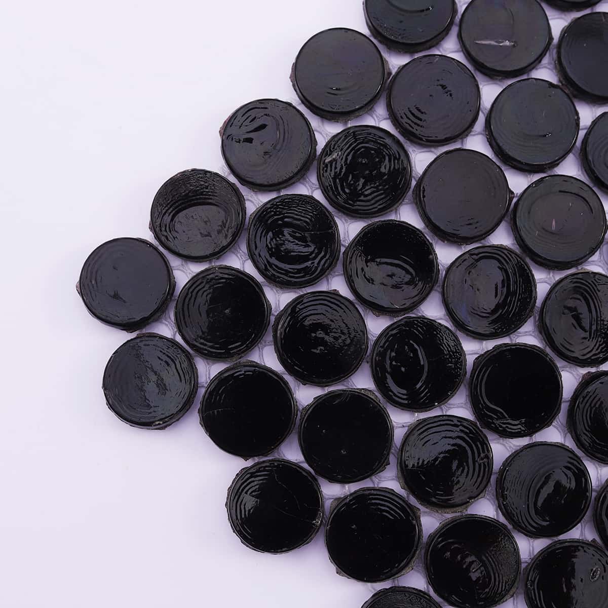 Close-up of the edge of black round mosaic tiles with textured surface