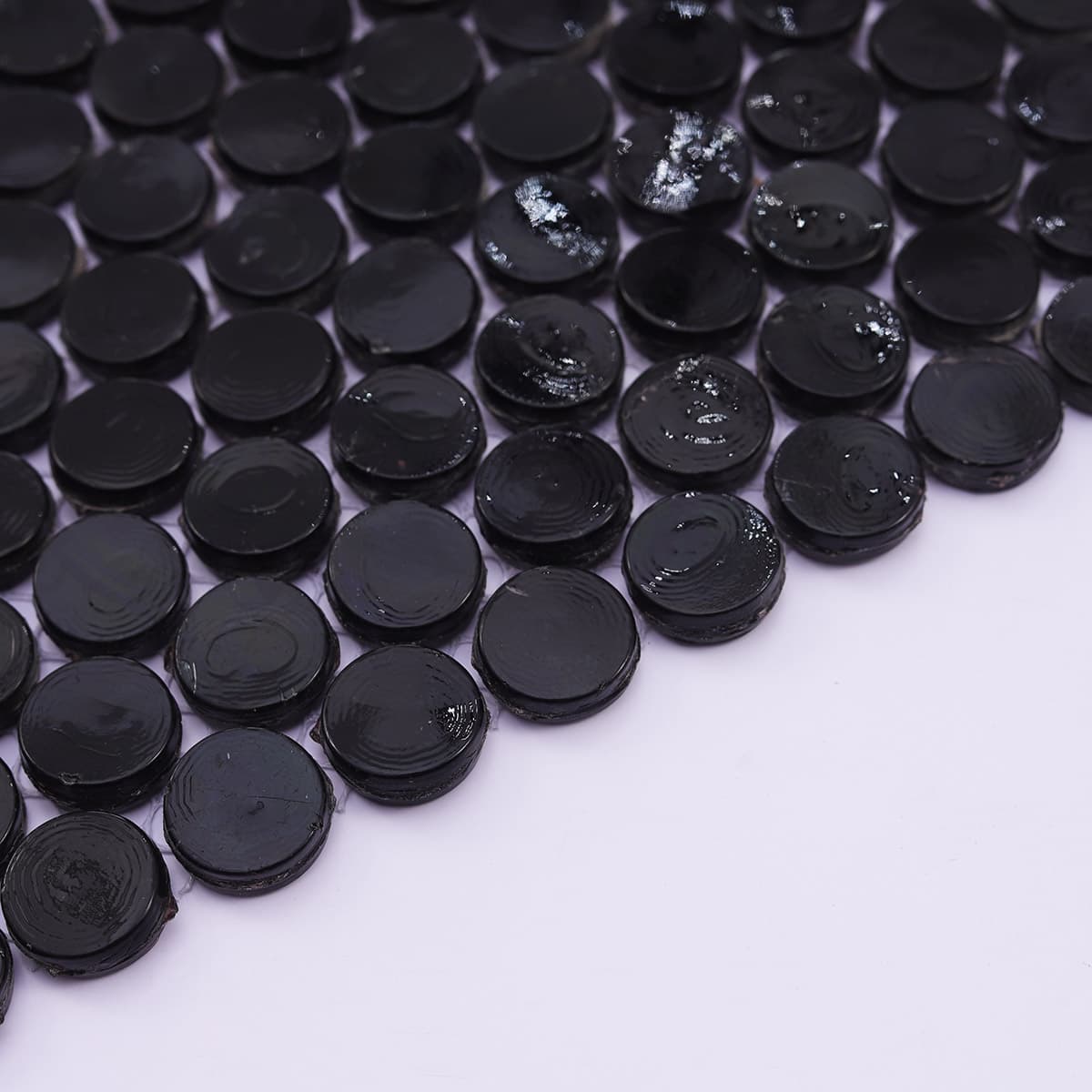 Edge detail of glossy black round mosaic tiles laid in a curve