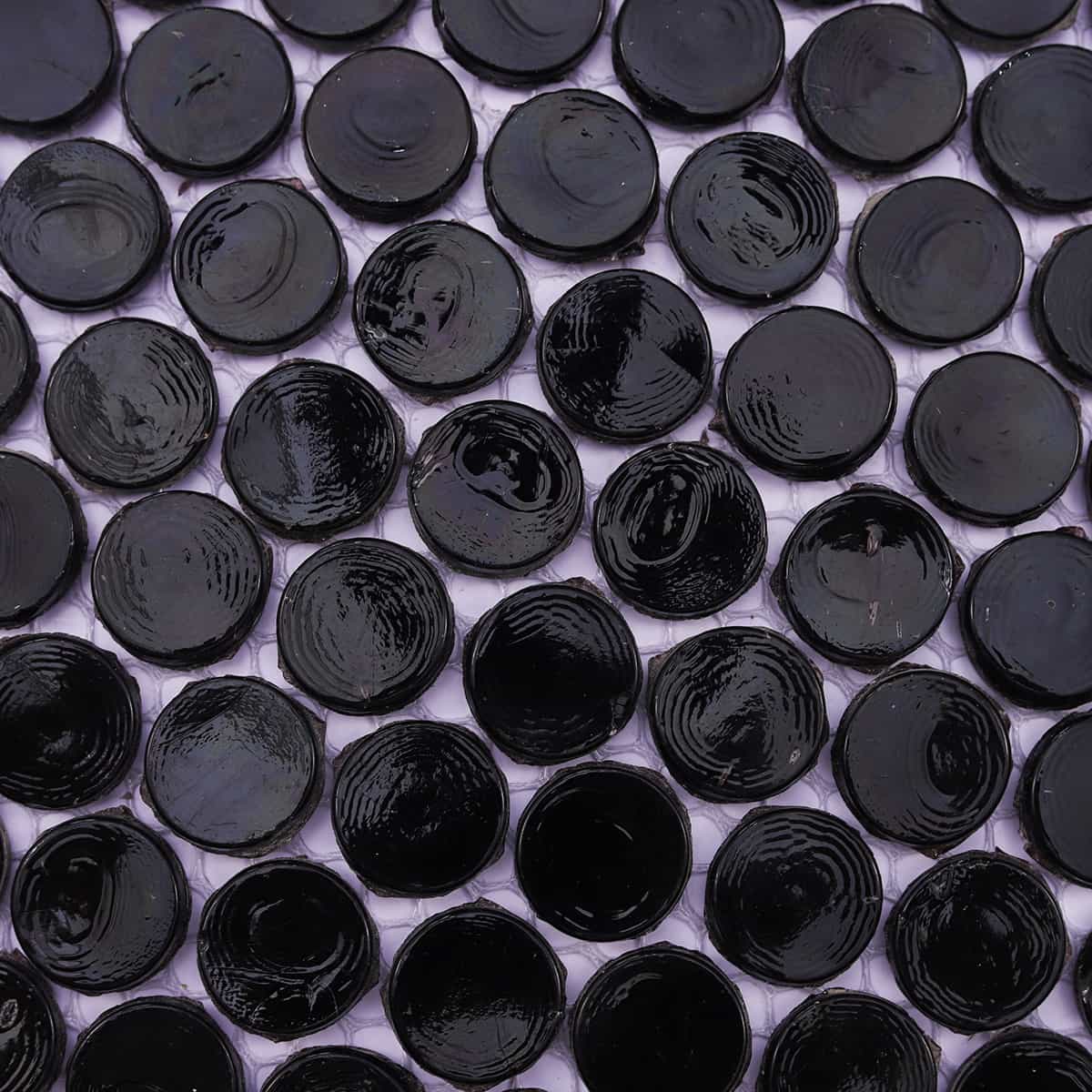 Detail view of black round mosaic tile surface with swirl texture