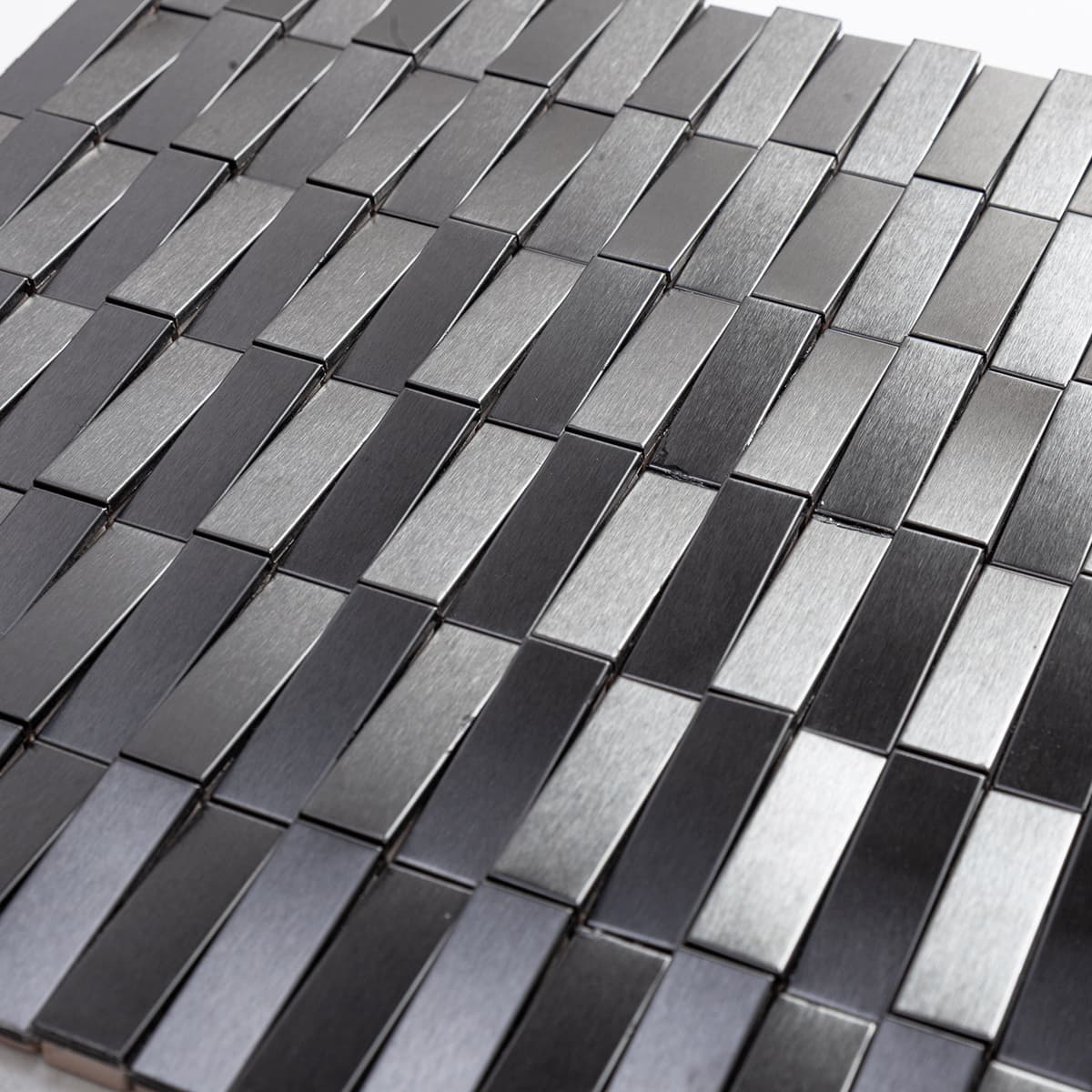 Close-up view of black stainless steel long strip 3D mosaic tiles showing brushed finish