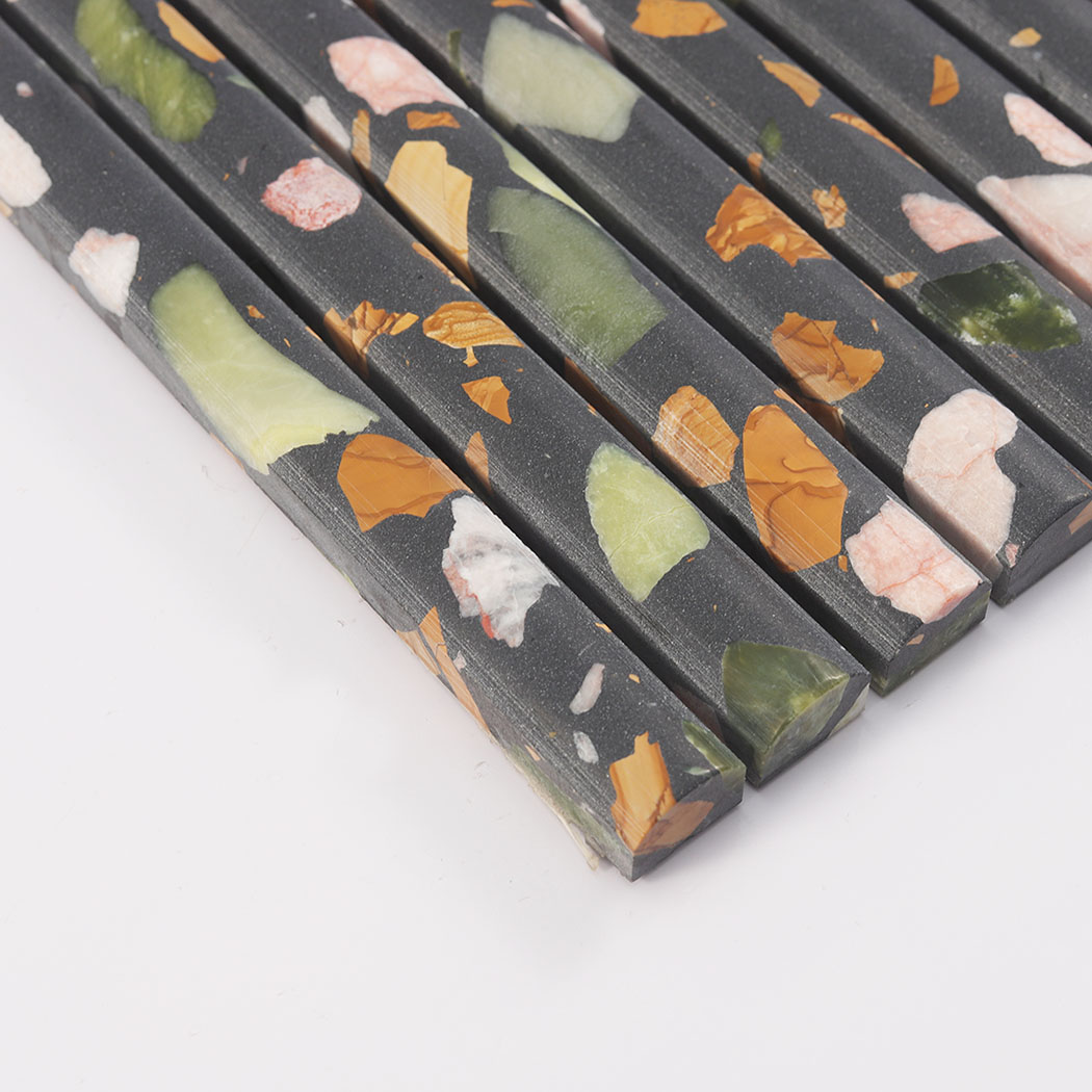 Edge close-up of black terrazzo fluted mosaic tile with green and amber chips
