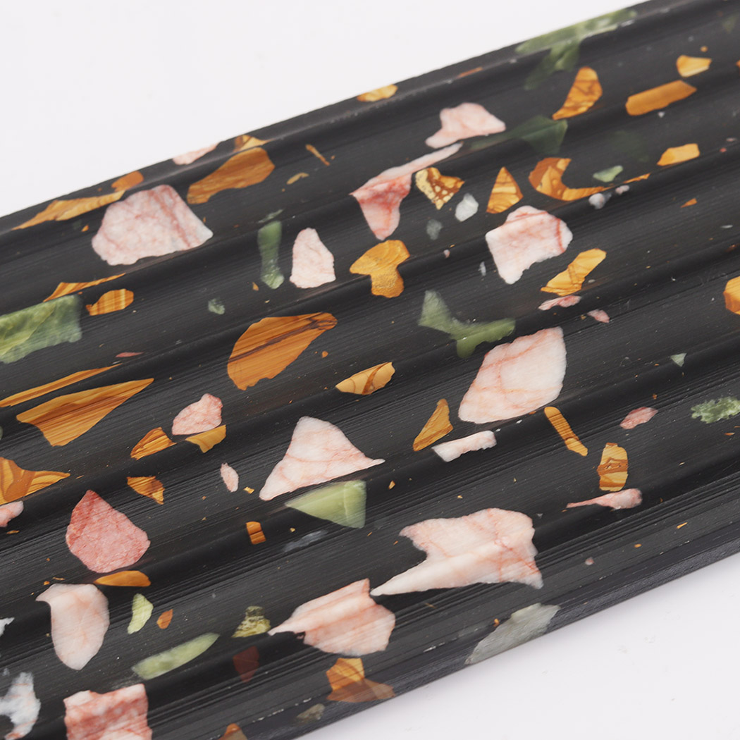 Close up of black terrazzo fluted tile with pink green and gold chips