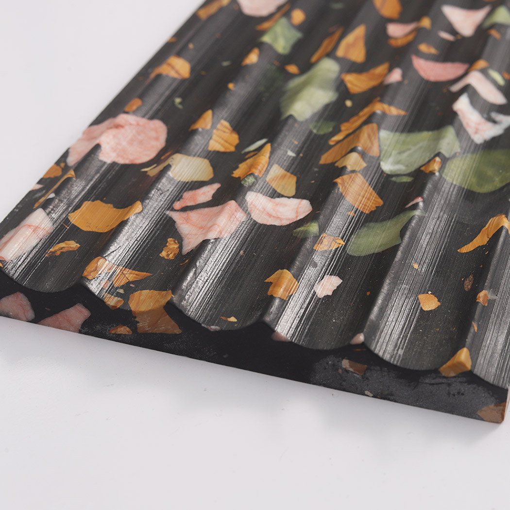 Rounded fluted edge of black terrazzo tile with colorful stone fragments