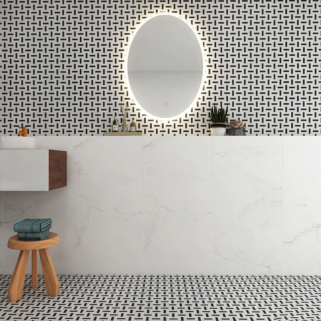 Black and white mosaic tile used on bathroom wall and floor with oval mirror