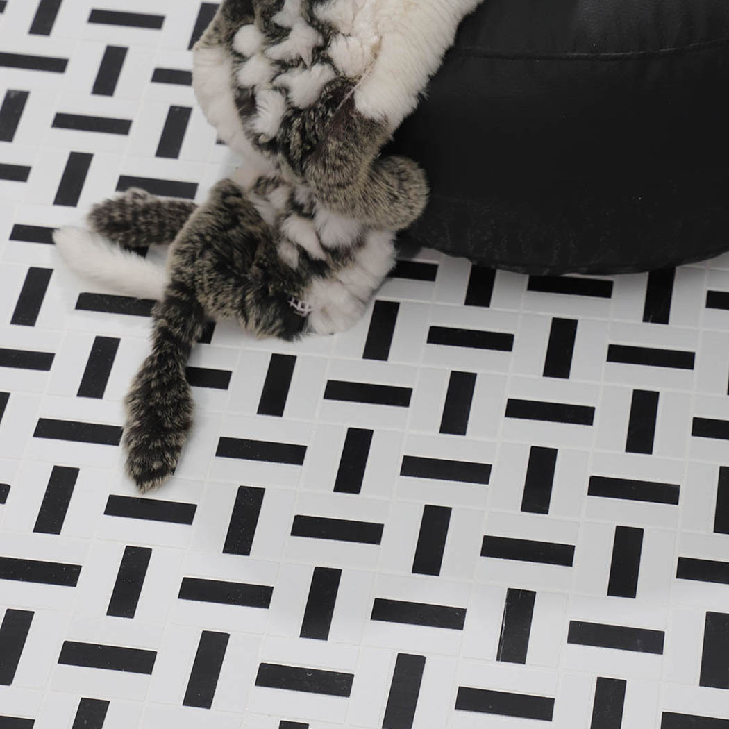 Close-up of black and white mosaic tile floor beside a black ottoman