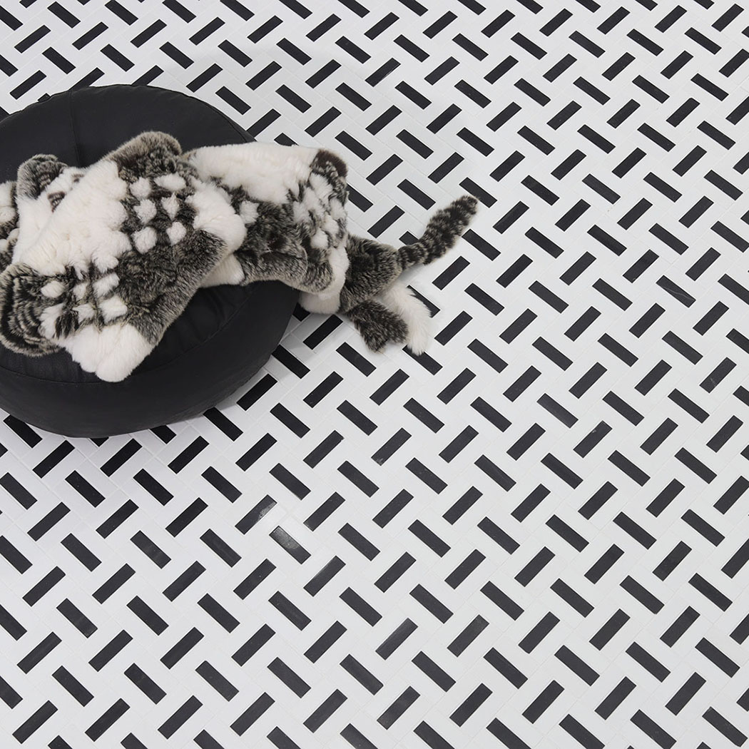 Black and white mosaic tile floor with a black round ottoman and fur throw