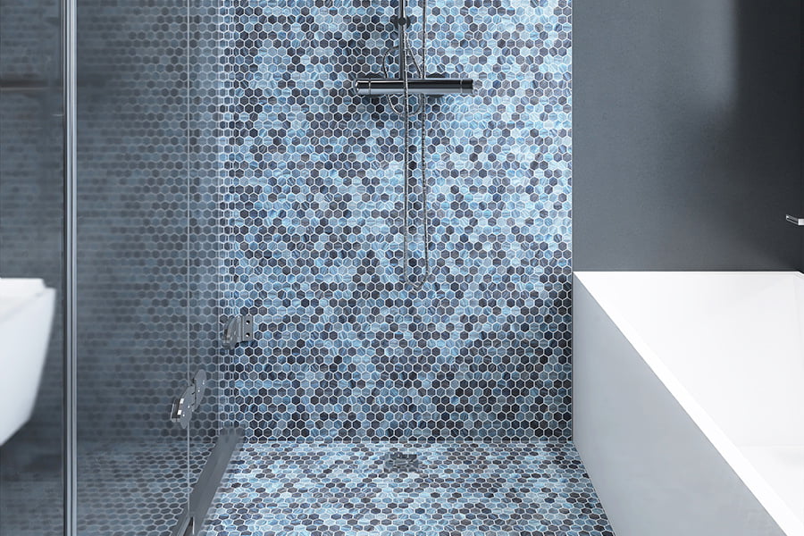 Close‑up of shower floor with blue and black glass hexagon mosaic tiles