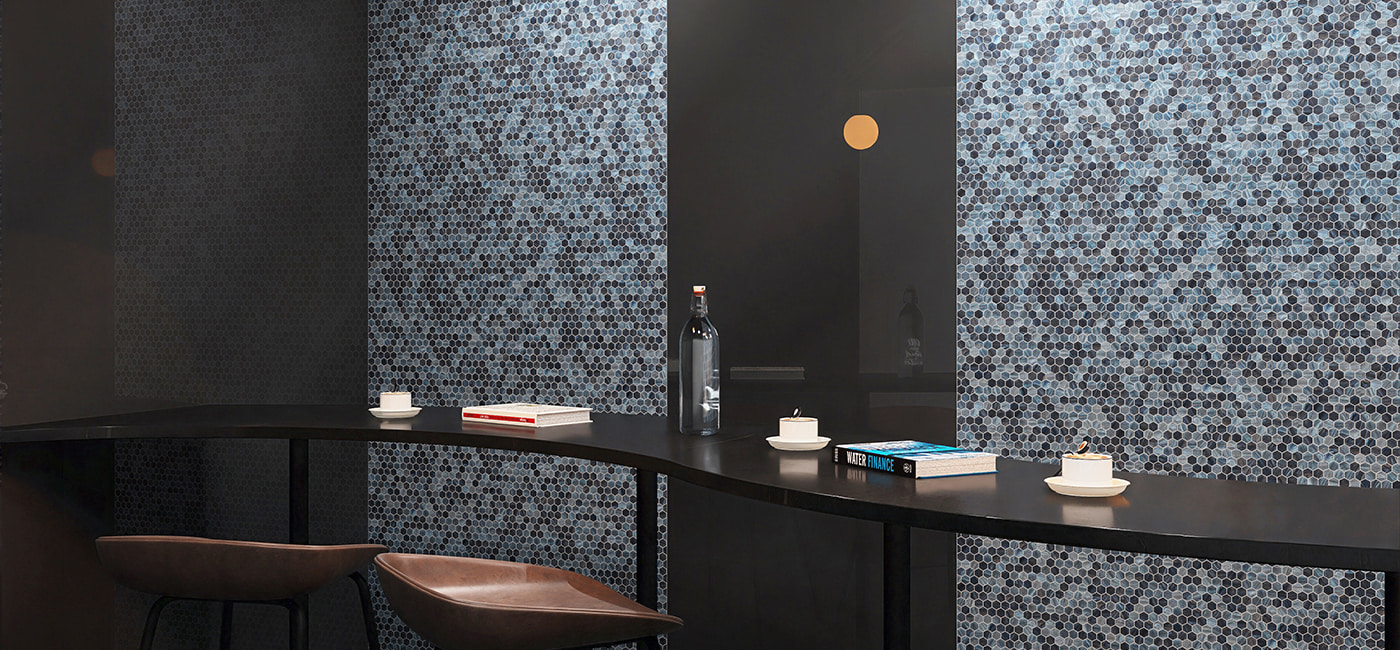 Dark-toned bar interior with flowing blue glass hexagon mosaic accent wall