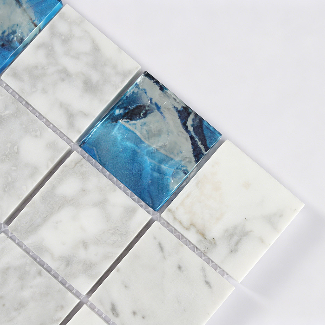Close detail of blue glass insert beside white marble square mosaic tiles