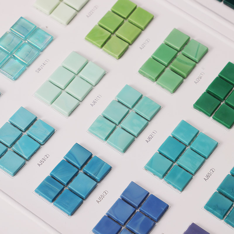 Blue and green square glass mosaic tile samples displayed on a color chart