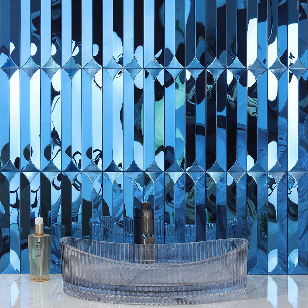 Blue mirror tile backsplash behind a fluted glass vessel sink on a white counter.