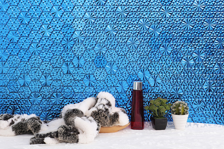 Bright blue hexagon mosaic tile wall with textured geometric pattern and bath accessories
