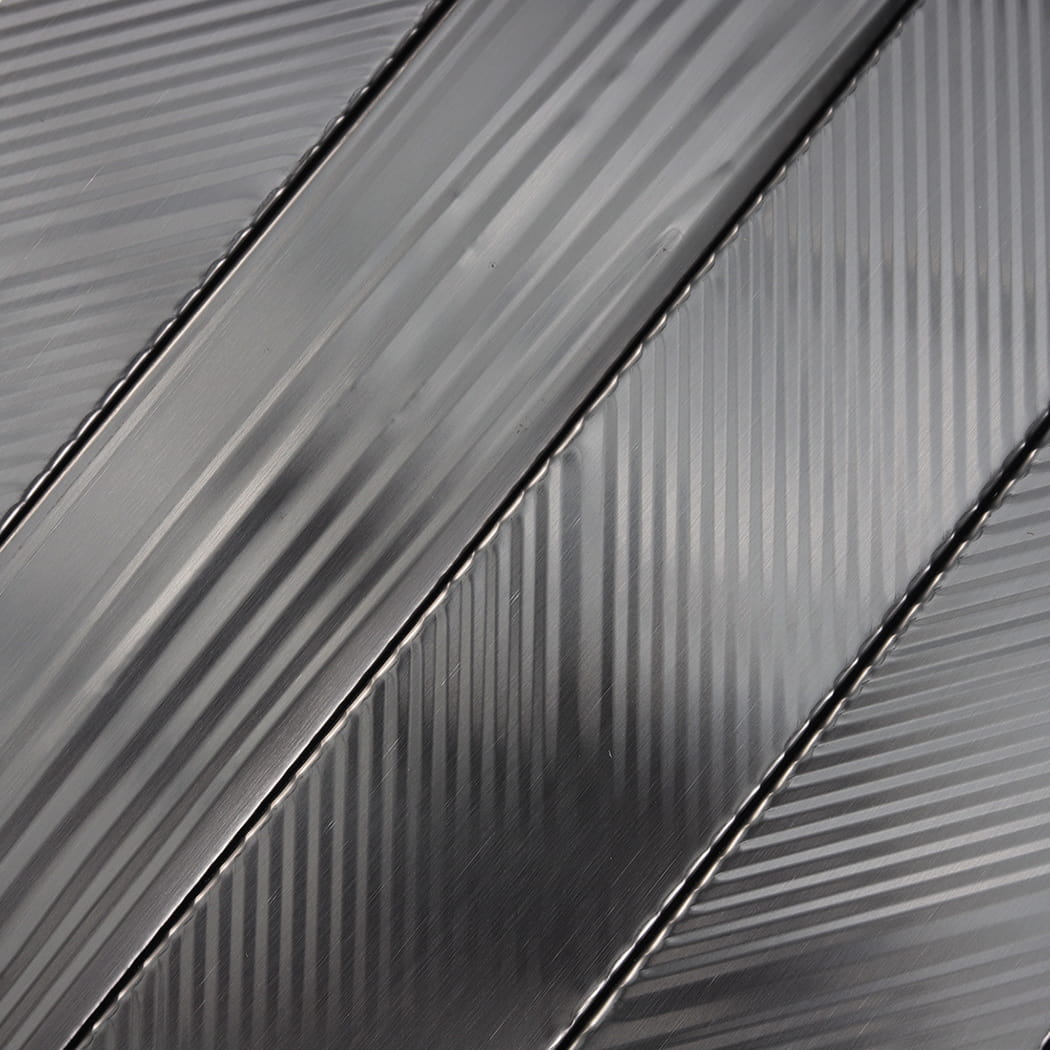 Close-up of brushed black stainless steel tiles with mixed diagonal and vertical grooves