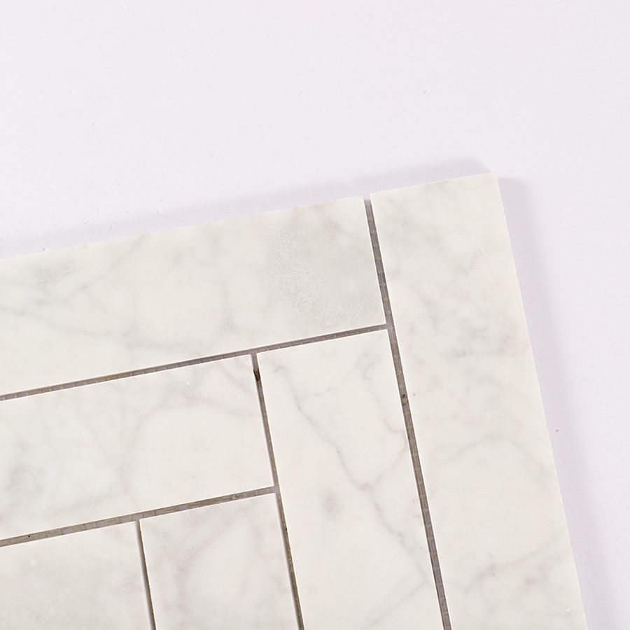 Corner close-up of Carrara white herringbone marble tile pattern