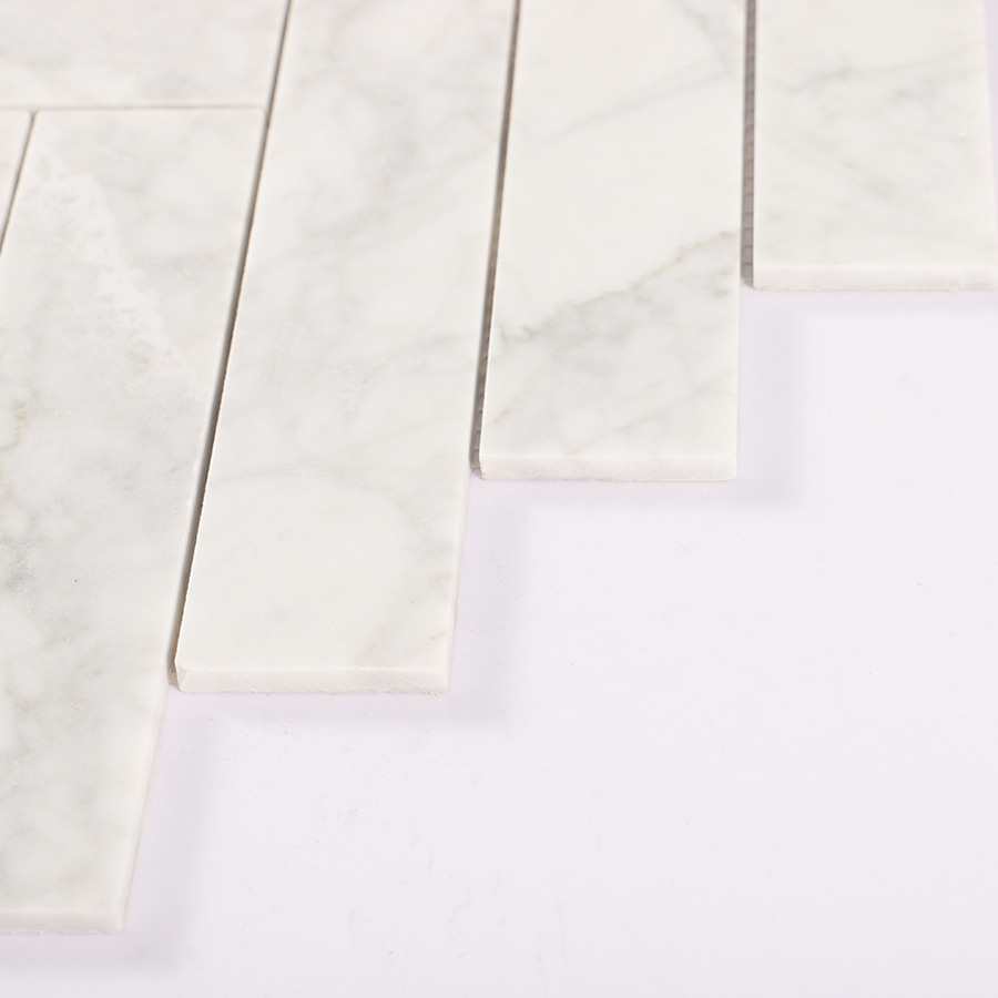 Edge close-up showing thickness of Carrara white herringbone tile