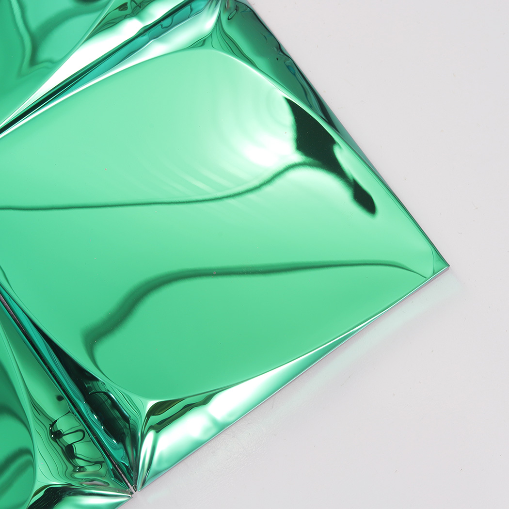 Close-up of the smooth curved corner of a green 3D mirror wall tile.