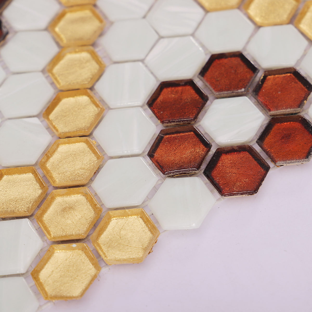 Close-up of white and gold hexagon glass mosaic with metallic red tiles