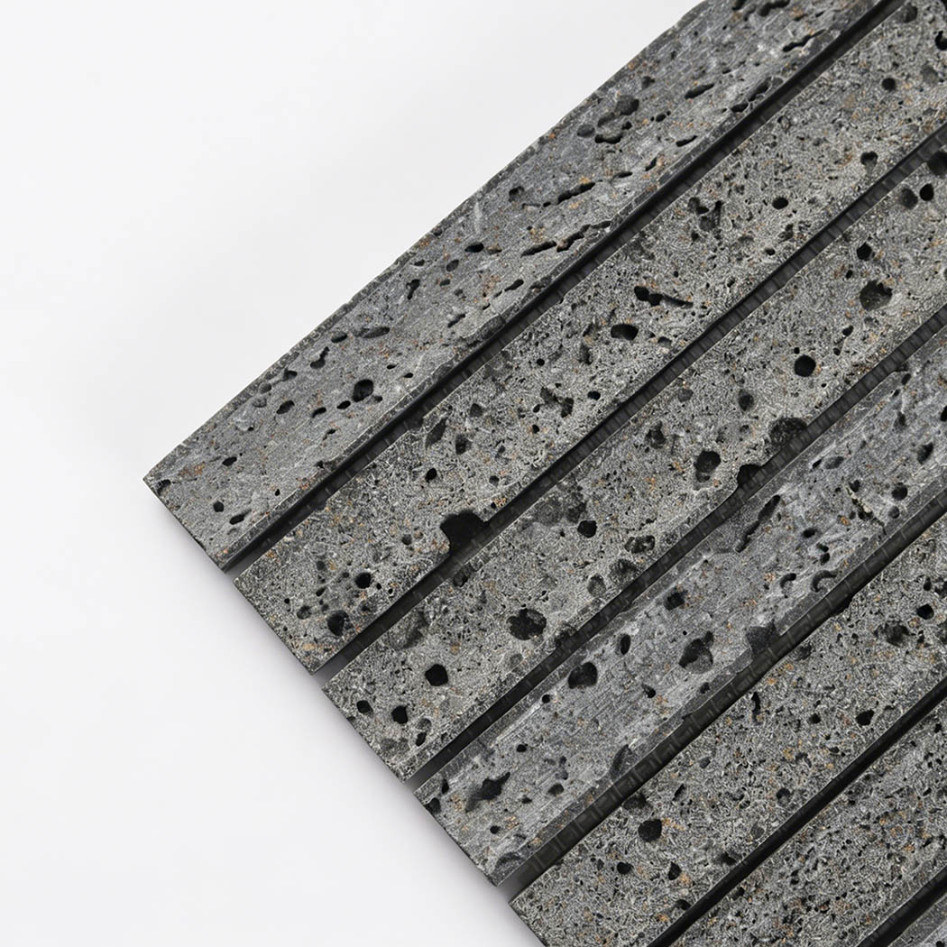 Close up corner view of gray lava stone linear mosaic tile with natural black pores