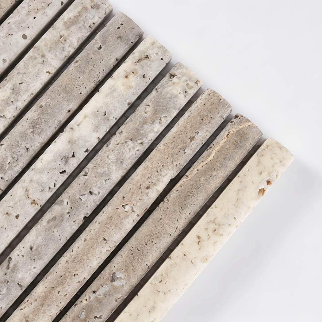 Close up corner view of gray travertine fluted mosaic tile showing natural pores