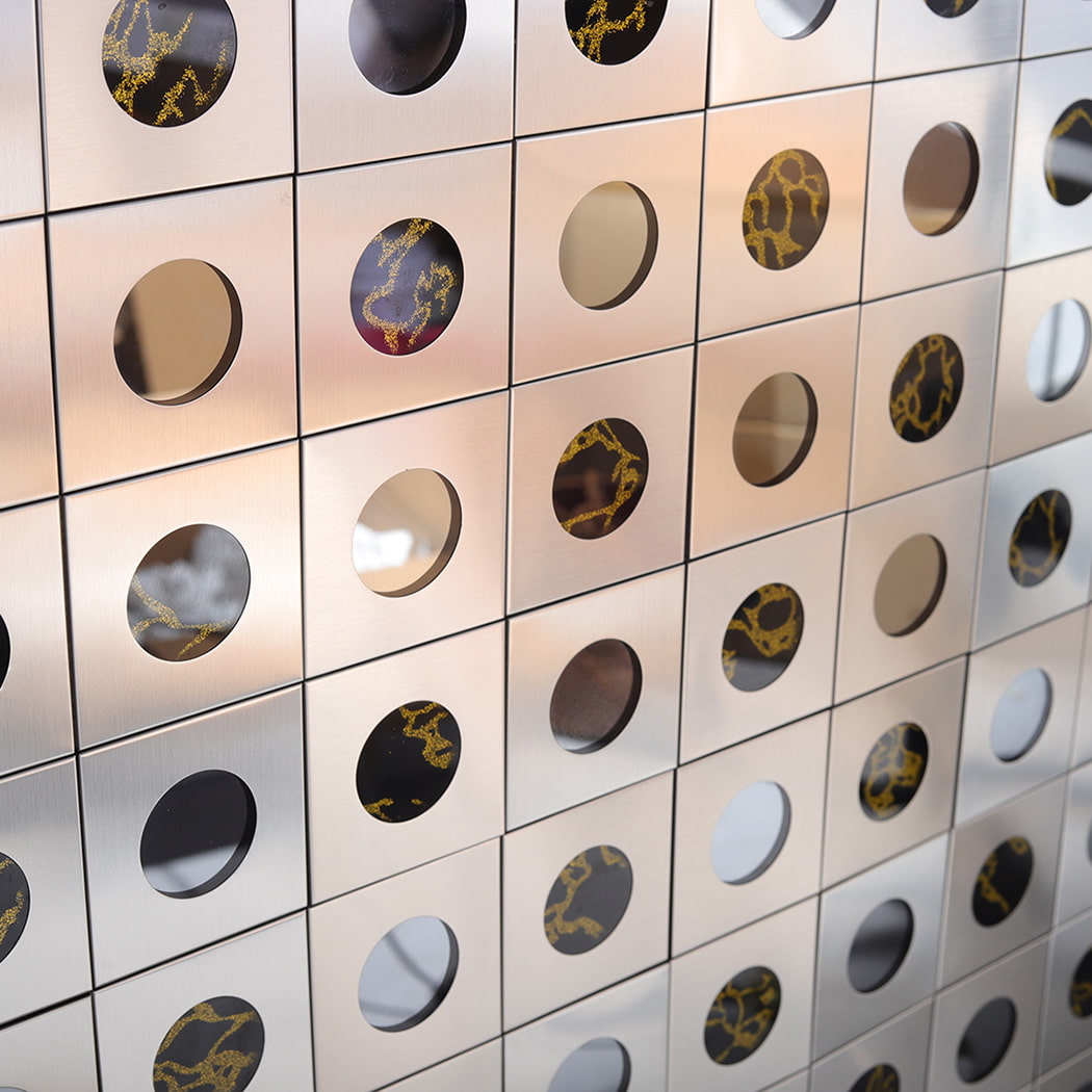 Close up of stainless steel round mirror wall mosaic showing light reflection.