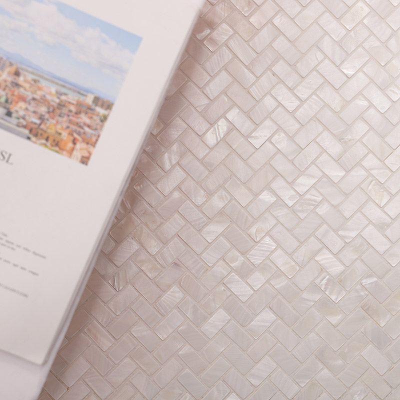 Close-up of white iridescent herringbone mosaic tile with a soft glossy sheen