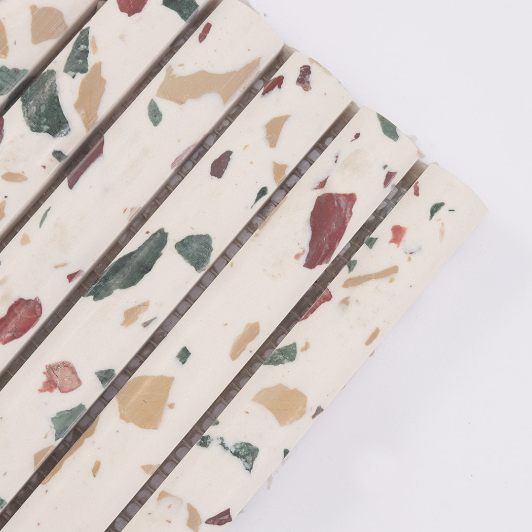 Close-up corner view of white terrazzo fluted tile with red and green chips