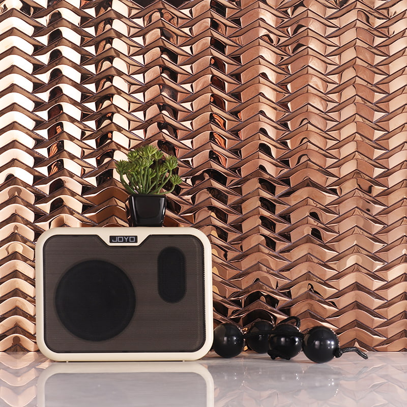 Retro speaker & succulent on countertop with copper herringbone tile backsplash.