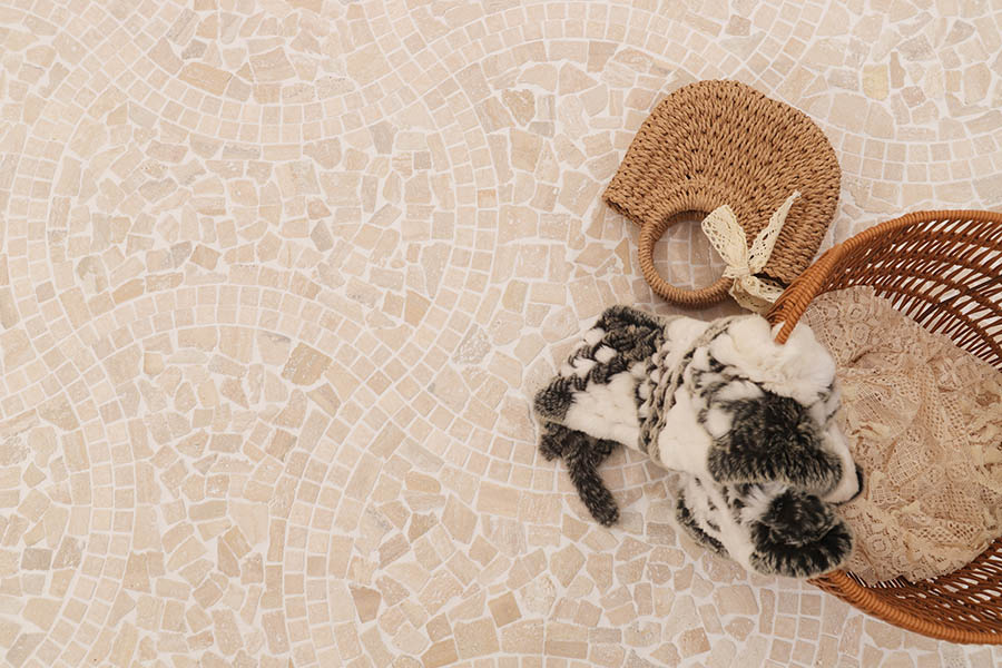 Cream travertine floor tile with natural mosaic pattern and woven basket decor