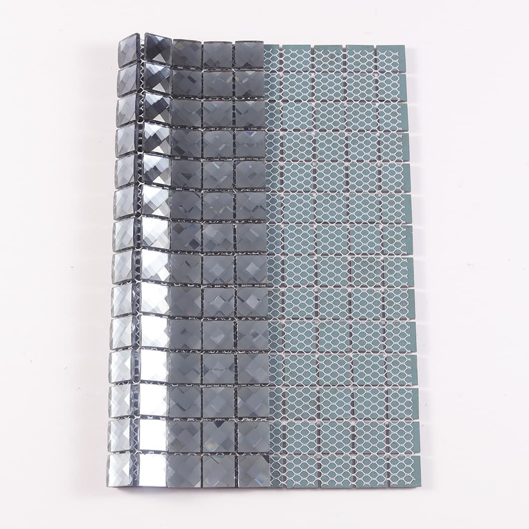 Dark grey glass mosaic tile folded to show the front design and the mesh backing.