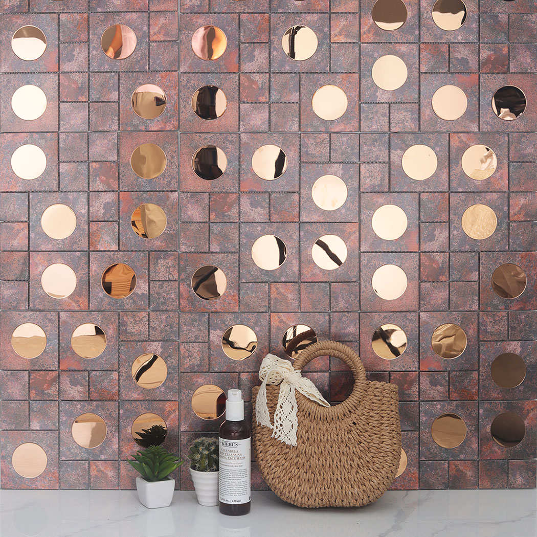 A dry decorative interior wall covered in patina bronze aluminum tiles behind a handbag.