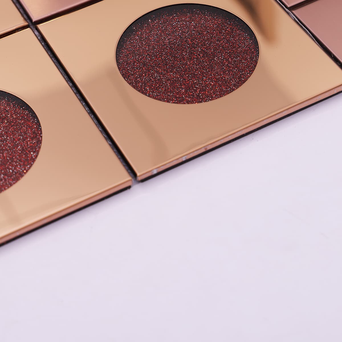 Edge close-up of rose gold and red glitter circle mosaic