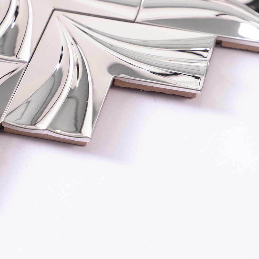 Edge view of chrome 3D stainless steel chevron tile on white background
