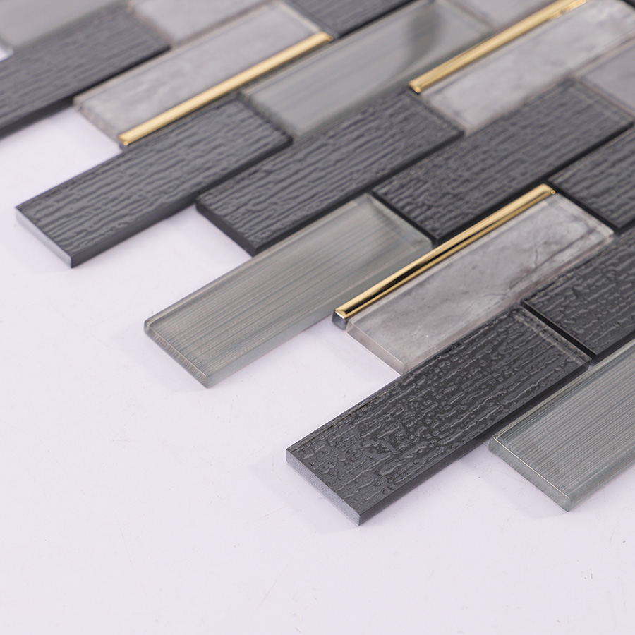 Edge view of dark grey subway glass wall tile with clear and gold trim pieces