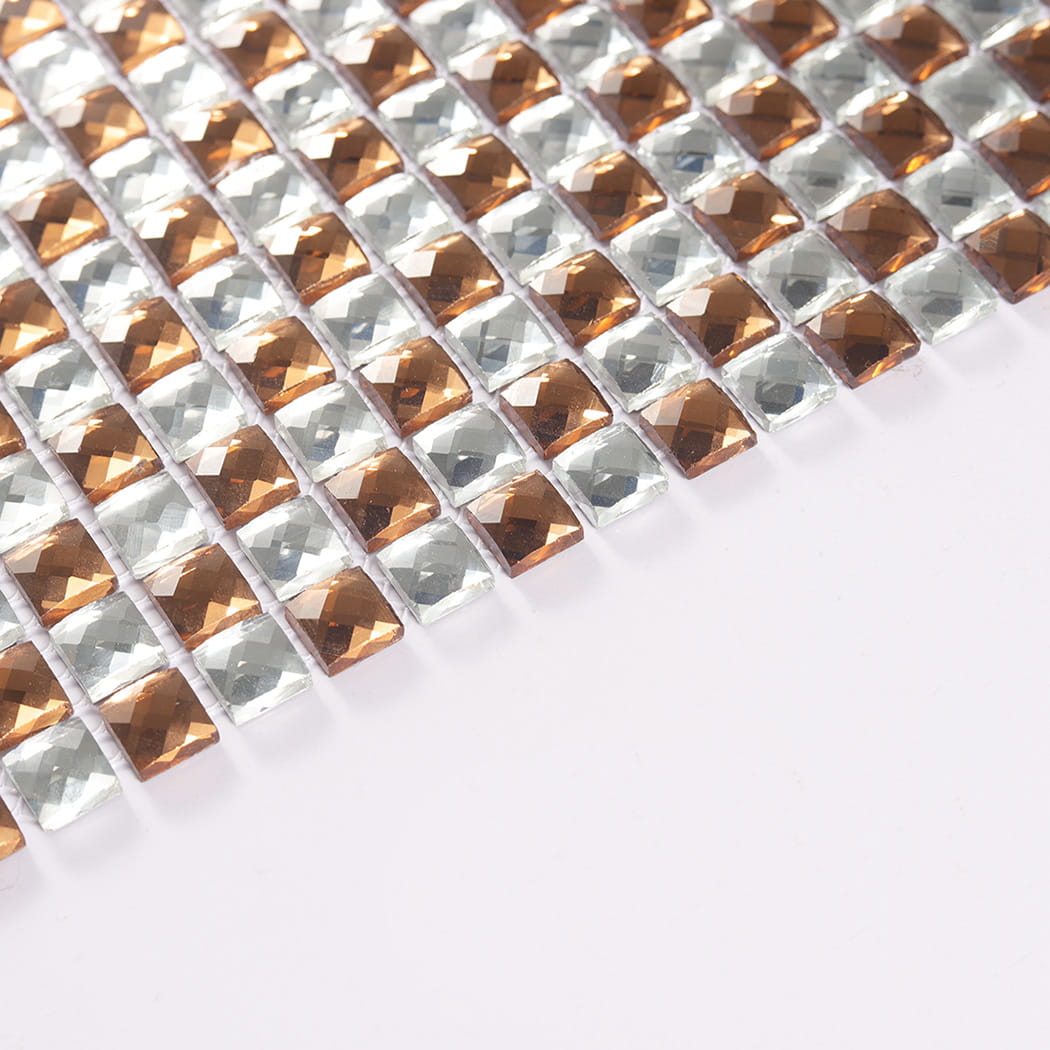 Angled edge view of small rose gold and silver diamond glass mosaic chips on white.