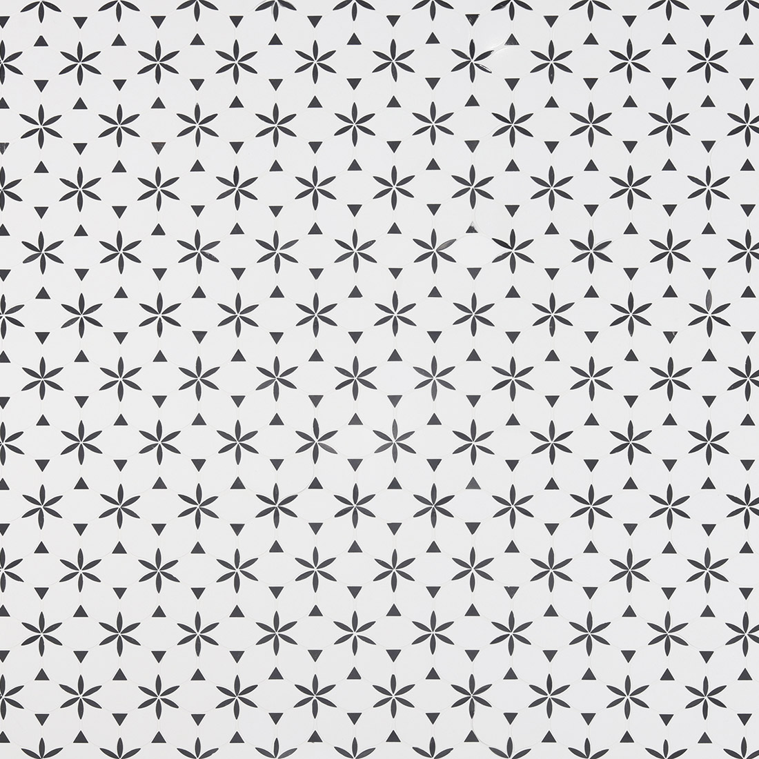 Full-frame pattern of black floral and triangle shapes on white mosaic floor tiles.