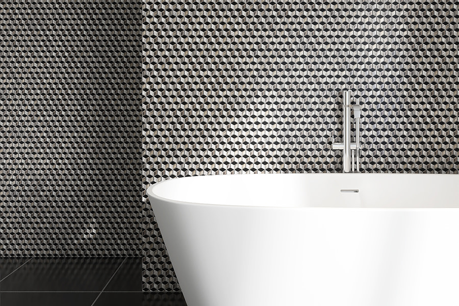 Black and silver cube mosaic tile wall behind a modern bathtub