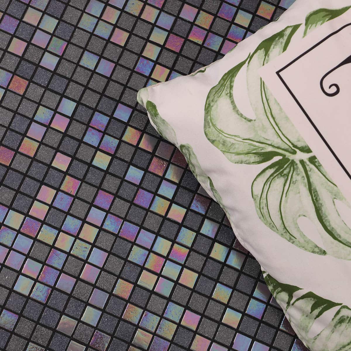 Top view of pillow on iridescent square mosaic tiles