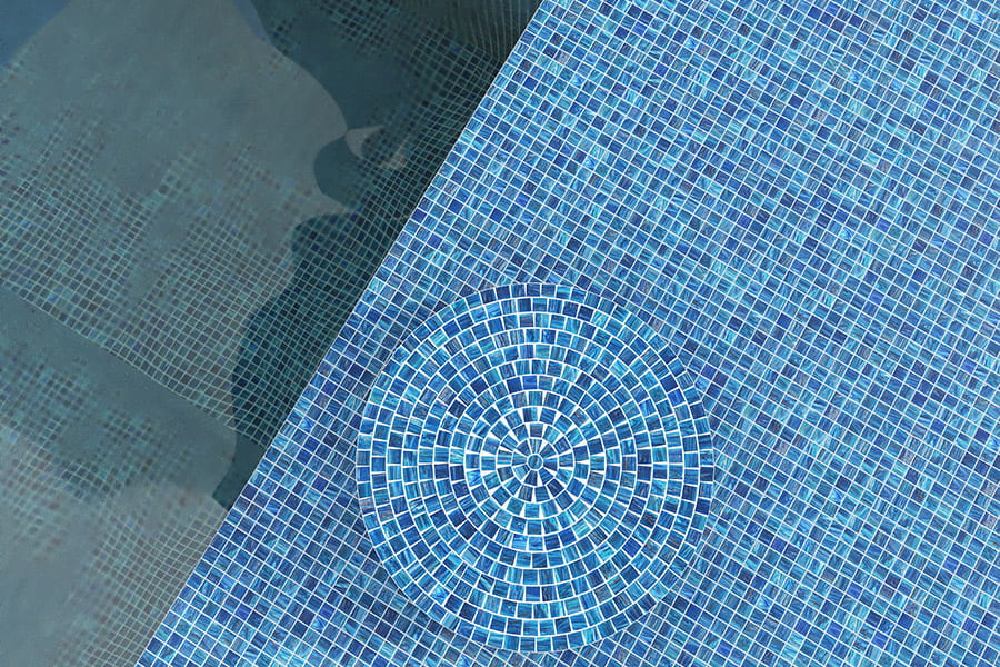 Glass pool tiles with circular blue mosaic pattern at poolside