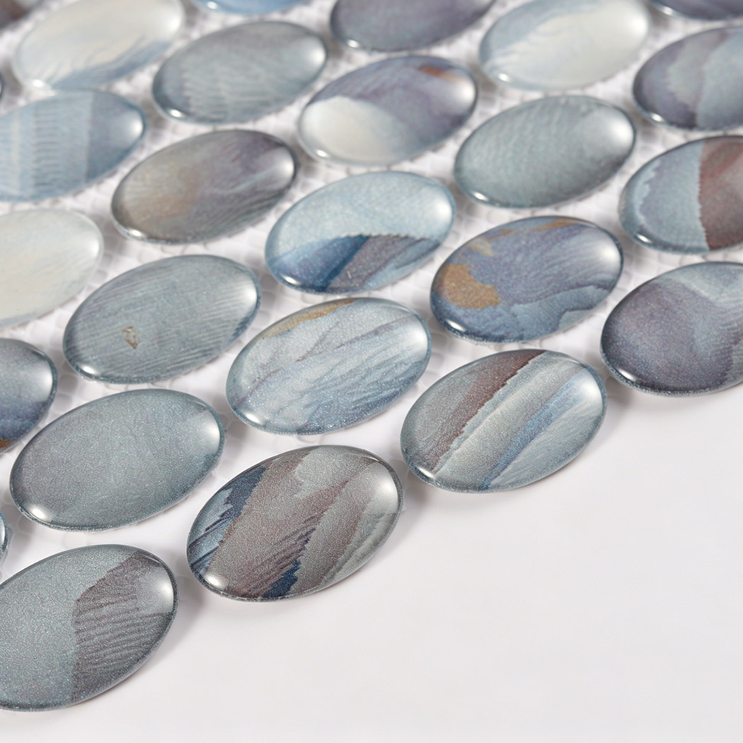 Low angle detail of glossy oval glass mosaic with blue gray and beige patterns