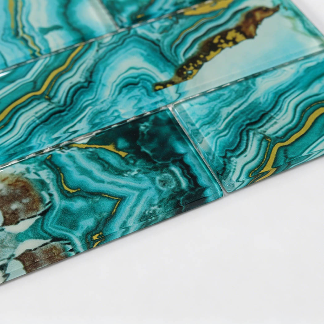Glossy teal glass subway tile edge showing agate swirls and gold line details