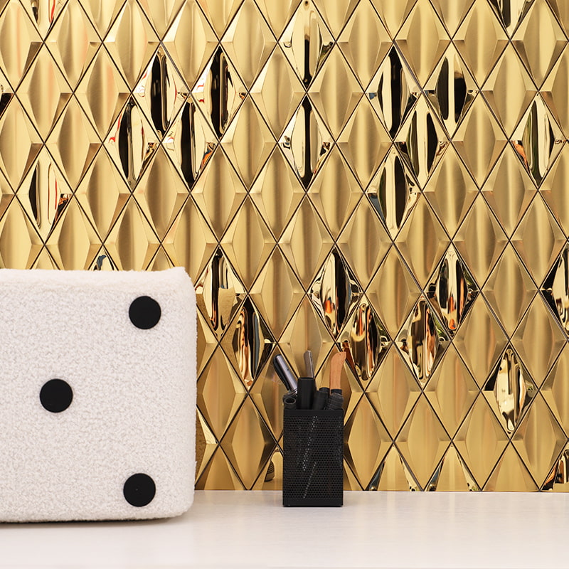 Close-up of gold 3D diamond metal tile wall with white cushion and black pen holder