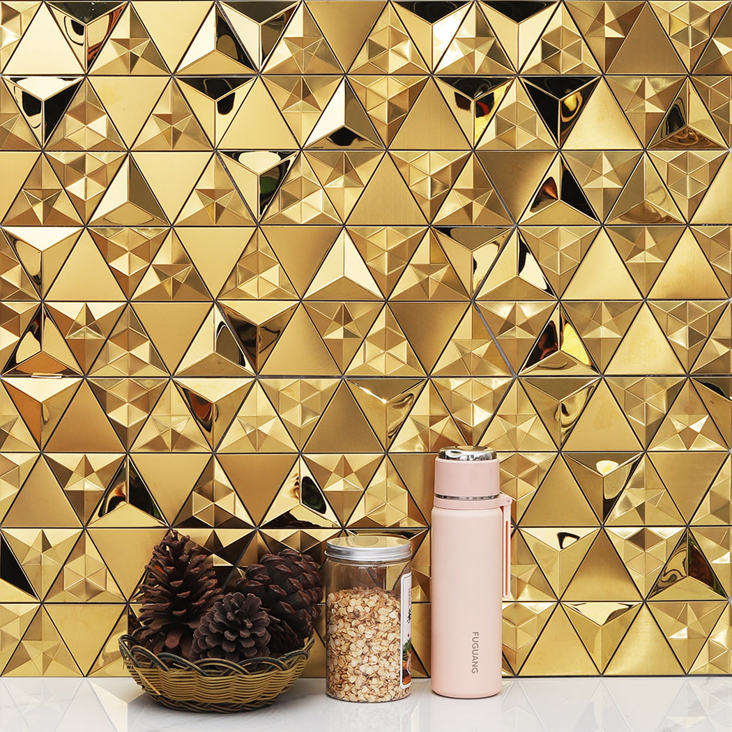 Gold geometric tiles used as a backsplash with decorative pine cones and a flask.