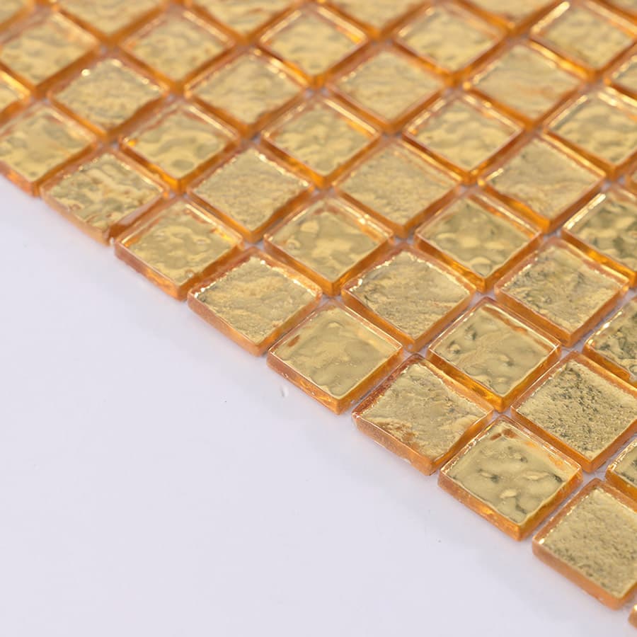 Side angle view of gold glass mosaic tile showing glossy edges.