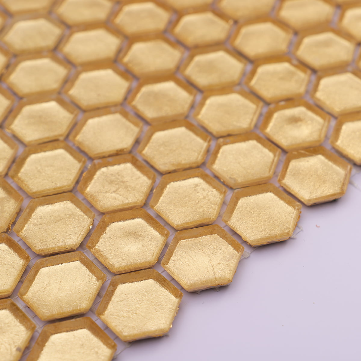Close-up of textured gold hexagon glass mosaic tiles showing rich surface detail