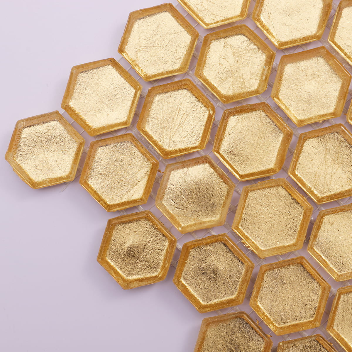 Corner detail of gold hexagon glass mosaic tiles with layered texture