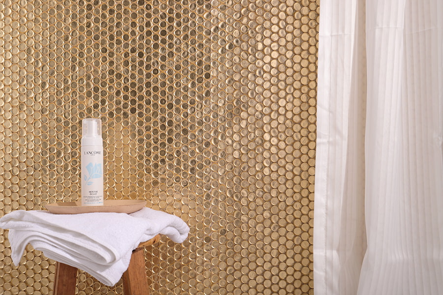 Gold penny round glass tiles used on a bathroom wall