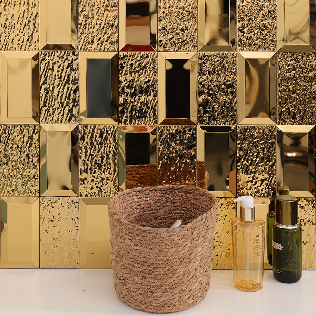 Gold mosaic tile wall background with basket and bottles on counter.